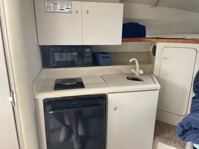 Slide: The Image of 1998 Cruisers 2870 Rogue boat kitchenette with microwave, sink, and stove. - 27