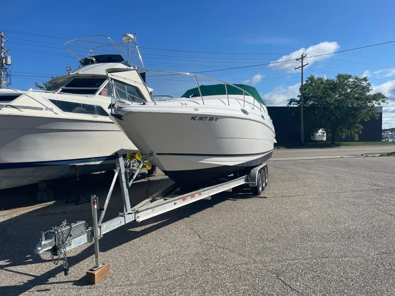 Slide: The Image of 1998 Cruisers 2870 Rogue boat on trailer, parked outdoors under clear blue sky. - 4