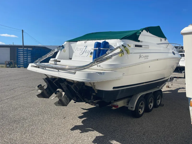 Slide: The Image of 1998 Cruisers 2870 Rogue boat on trailer, parked outdoors under clear blue sky. - 7