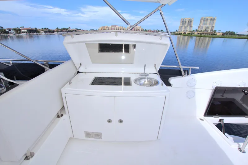 Slide: The Image of Outdoor kitchenette on a 2015 Dyna 60 yacht with sink and grill, overlooking serene waterfront. - 13