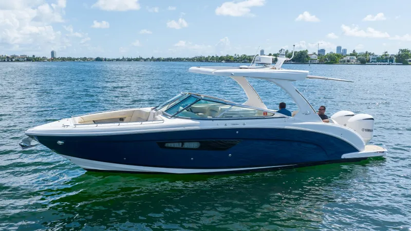 Slide: The Image of 2019 Regal 33 OBX boat cruising on a sunny day with city skyline in background. - 10