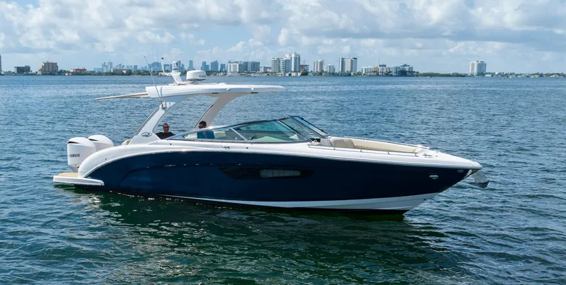 Slide: The Image of 2019 Regal 33 OBX boat cruising on a calm sea with city skyline in background. - 12