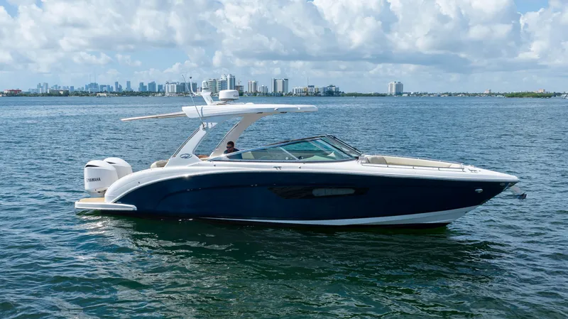 Slide: The Image of 2019 Regal 33 OBX boat cruising on a sunny day with city skyline in background. - 13