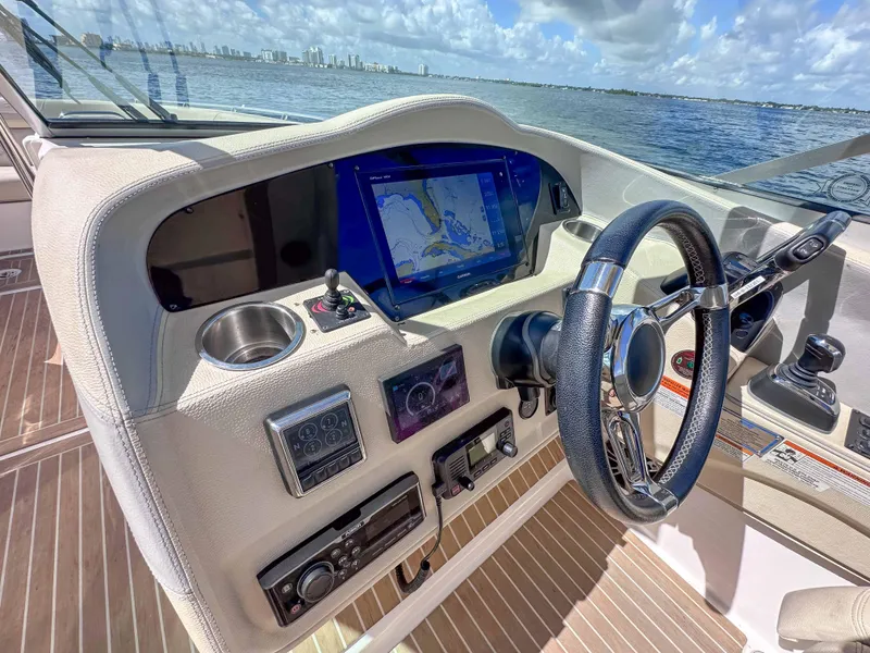 Slide: The Image of 2019 Regal 33 OBX boat dashboard with navigation screen, steering wheel, and controls. - 17