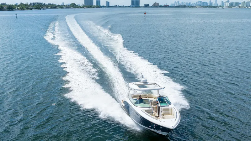 Slide: The Image of 2019 Regal 33 OBX boat cruising on open water, leaving a wake behind. - 2