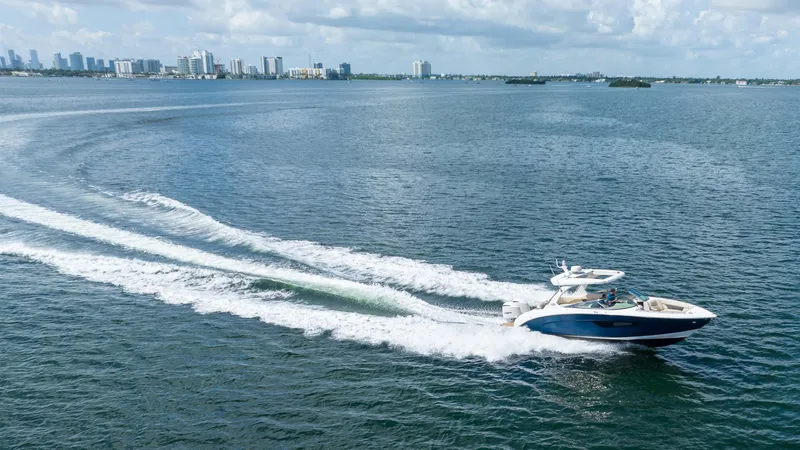 Slide: The Image of 2019 Regal 33 OBX boat cruising on open water with city skyline in background. - 7