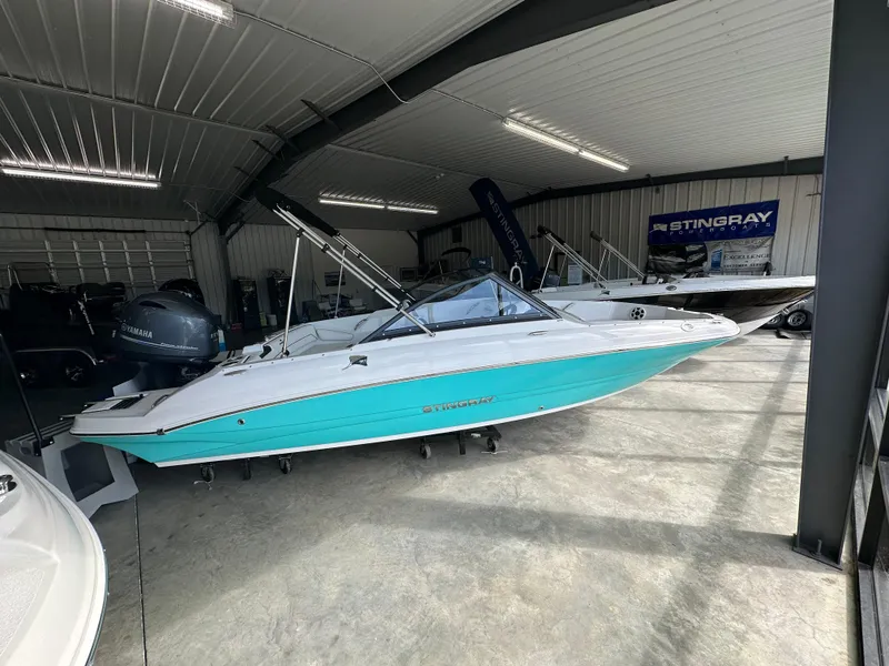 The Image of 2026 Stingray 191 DC boat in showroom, turquoise and white design, under bright lighting. - 1