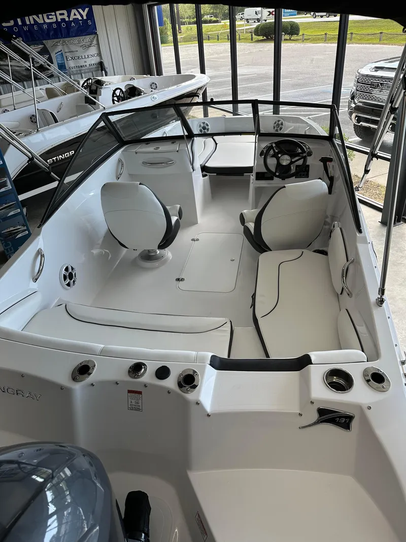 Slide: The Image of 2026 Stingray 191 DC boat interior with white seating and steering wheel in showroom. - 2