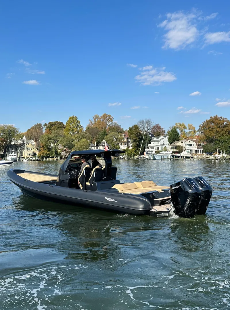 Slide: The Image of 2023 Ribco Seafarer 36 X boat cruising on a scenic lake with houses in the background. - 3