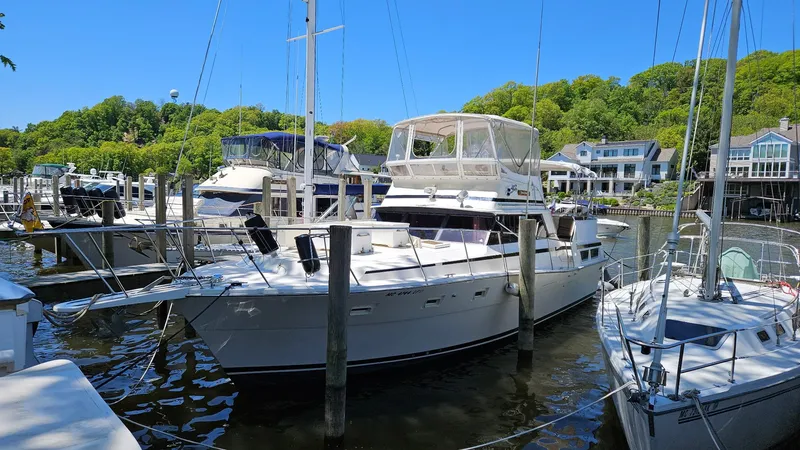 Slide: The Image of 1980 Viking 43 Double Cabin yacht docked at a marina, surrounded by other boats and lush greenery. - 2