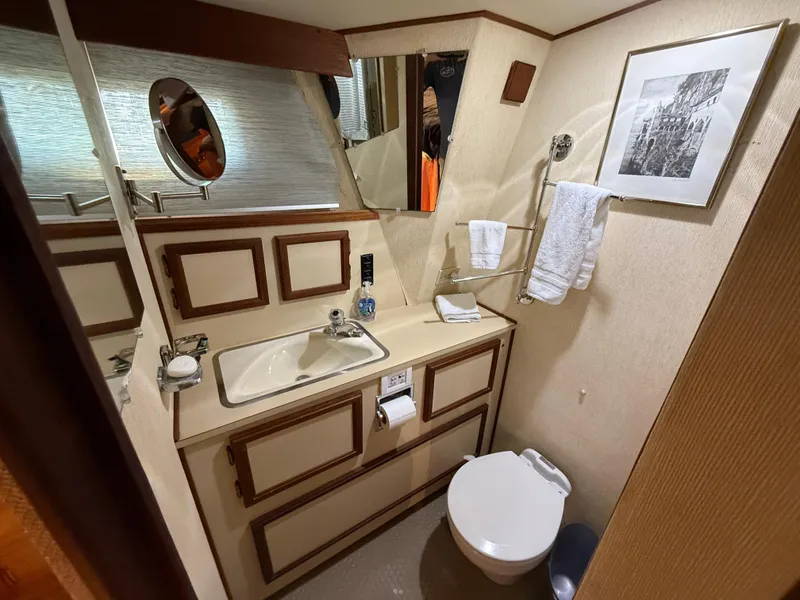 Slide: The Image of 1980 Viking 43 Double Cabin bathroom with sink, toilet, and framed artwork. - 29
