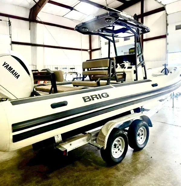 Slide: The Image of 2026 Brig Navigator boat with Yamaha engine on a trailer in a warehouse. - 2