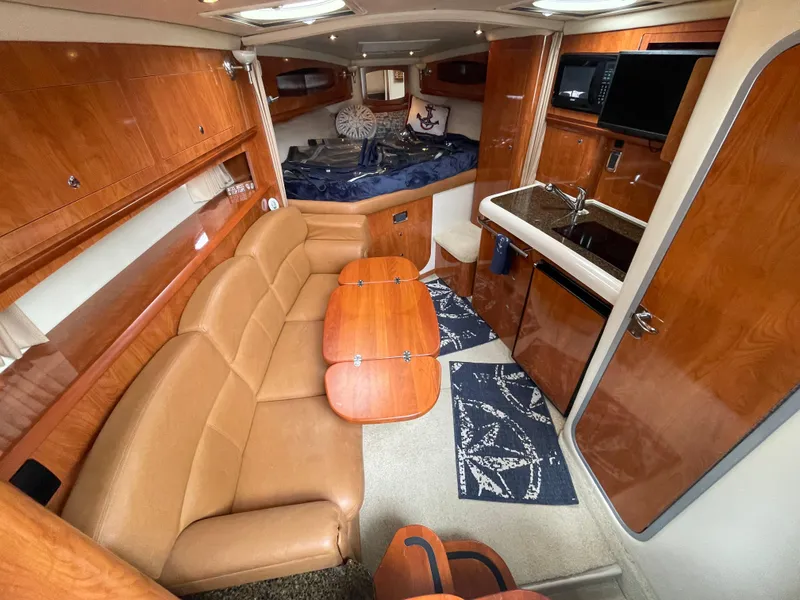 Slide: The Image of 2006 Four Winns 318 Vista cabin interior with leather seating, kitchenette, and wood finishes. - 23