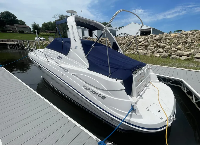 Slide: The Image of 2006 Four Winns 318 Vista boat docked, featuring a sleek design and blue canopy. - 3
