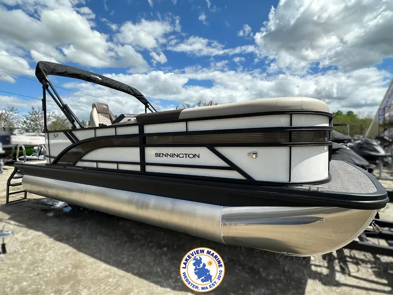 Slide: The Image of 2025 Bennington 21 SL pontoon boat under a partly cloudy sky. - 0