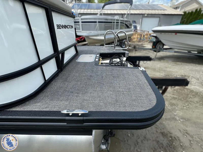 Slide: The Image of 2025 Bennington 21 SL pontoon boat rear deck with ladder, parked outdoors. - 1