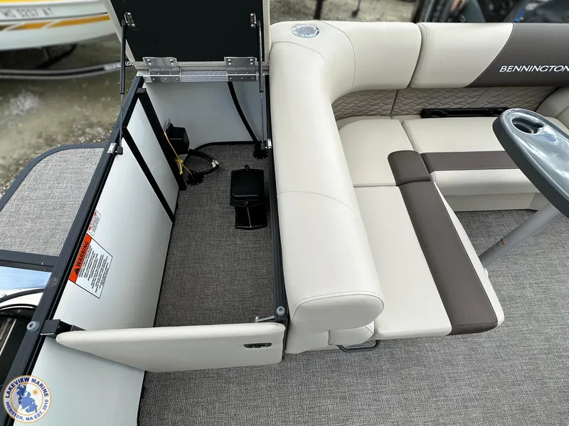 Slide: The Image of 2025 Bennington 21 SL boat interior with open storage compartment and cushioned seating. - 13