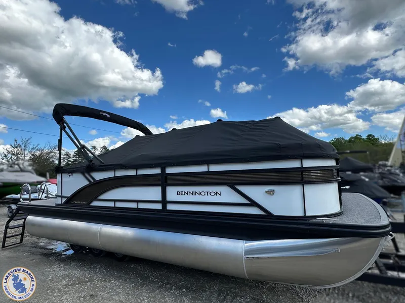 Slide: The Image of 2025 Bennington 21 SL pontoon boat with black cover under a blue sky. - 15