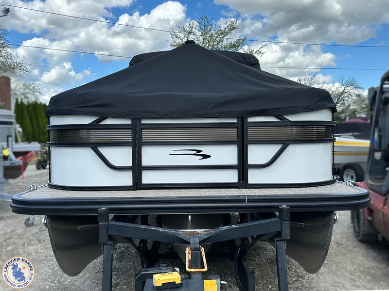 Slide: The Image of 2025 Bennington 21 SL pontoon boat with black cover, parked outdoors under cloudy sky. - 16