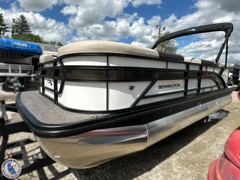 Slide: The Image of 2025 Bennington 21 SL pontoon boat with sleek design, parked outdoors under cloudy sky. - 2