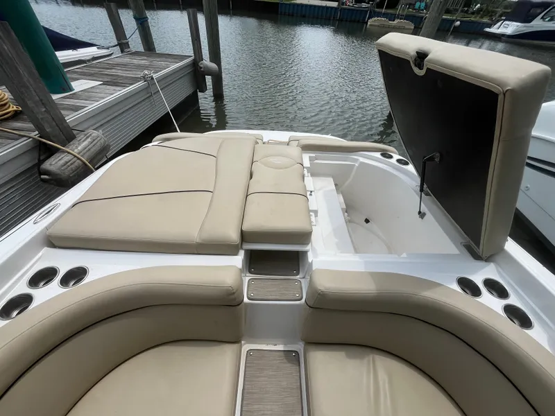 Slide: The Image of 2015 Rinker 276 Captiva Cuddy boat interior with beige seating and open storage compartment. - 12