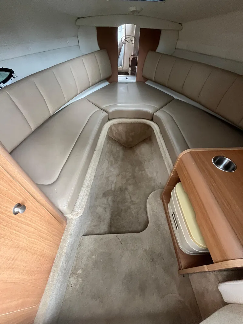 Slide: The Image of 2015 Rinker 276 Captiva Cuddy cabin interior with beige seating and wooden accents. - 15