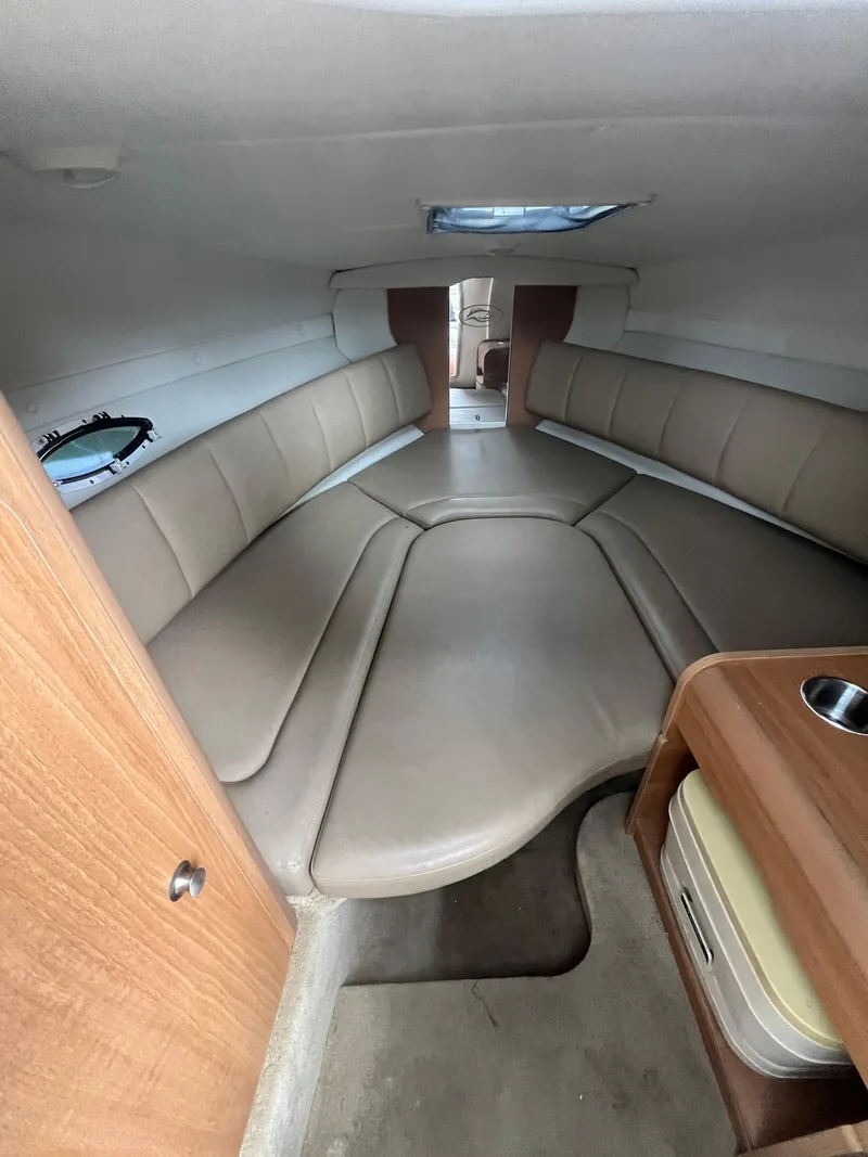 Slide: The Image of 2015 Rinker 276 Captiva Cuddy interior with beige seating and wooden accents. - 16