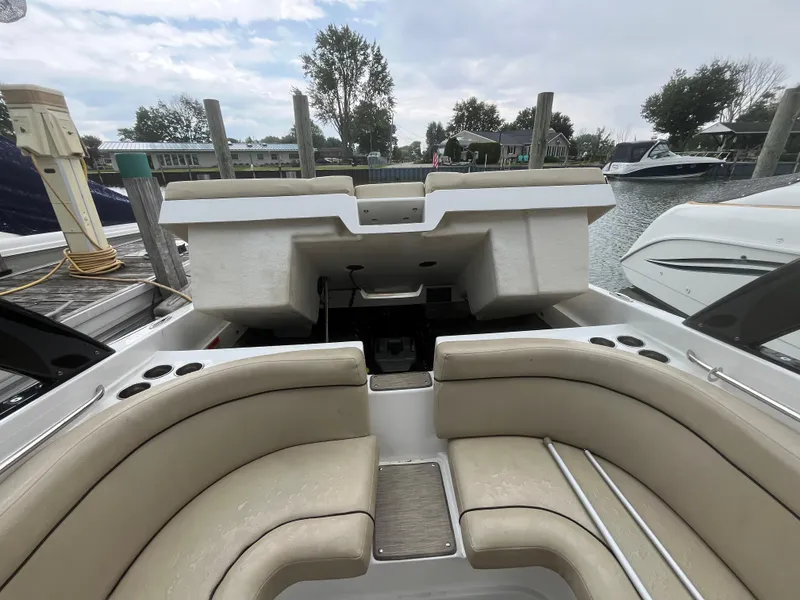 Slide: The Image of 2015 Rinker 276 Captiva Cuddy boat interior with beige seating at a dock. - 9