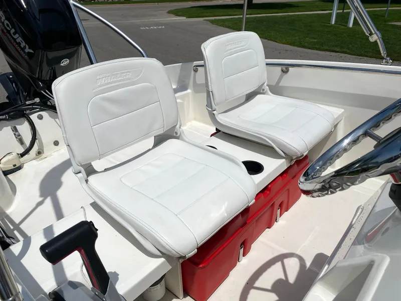 Slide: The Image of 2017 Boston Whaler 150 Super Sport boat interior with white seats and red storage. - 13