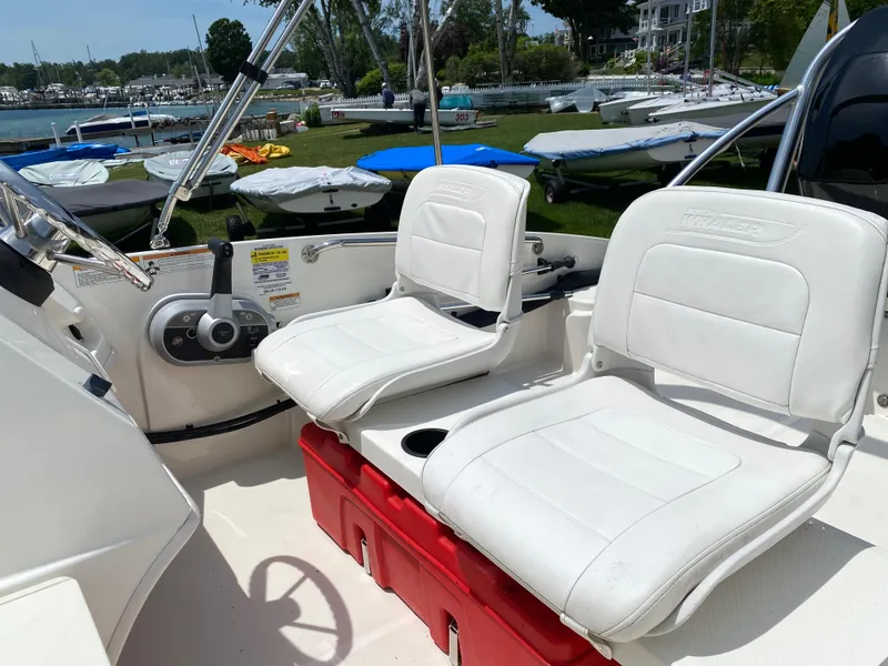 Slide: The Image of 2017 Boston Whaler 150 Super Sport interior with white seats and red storage box. - 14