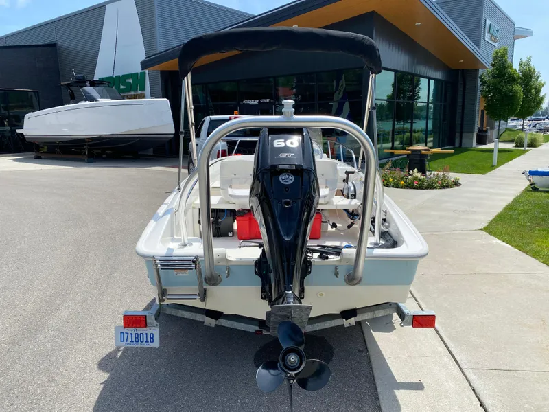 Slide: The Image of 2017 Boston Whaler 150 Super Sport boat with outboard motor, parked outside dealership. - 2