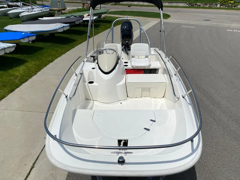 Slide: The Image of 2017 Boston Whaler 150 Super Sport boat, white interior, docked on pavement. - 8