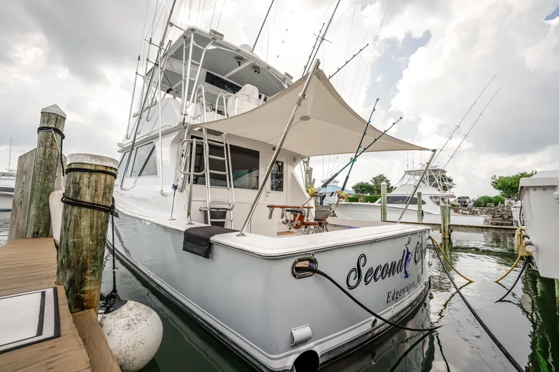 Slide: The Image of 1995 Viking 50 yacht docked, featuring fishing rods and canopy, named "Second Chance." - 18