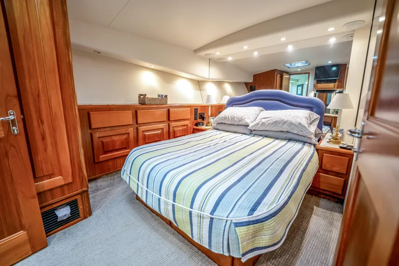 Slide: The Image of Luxurious bedroom interior on a 1995 Viking 50 yacht, featuring wood paneling and striped bedding. - 27