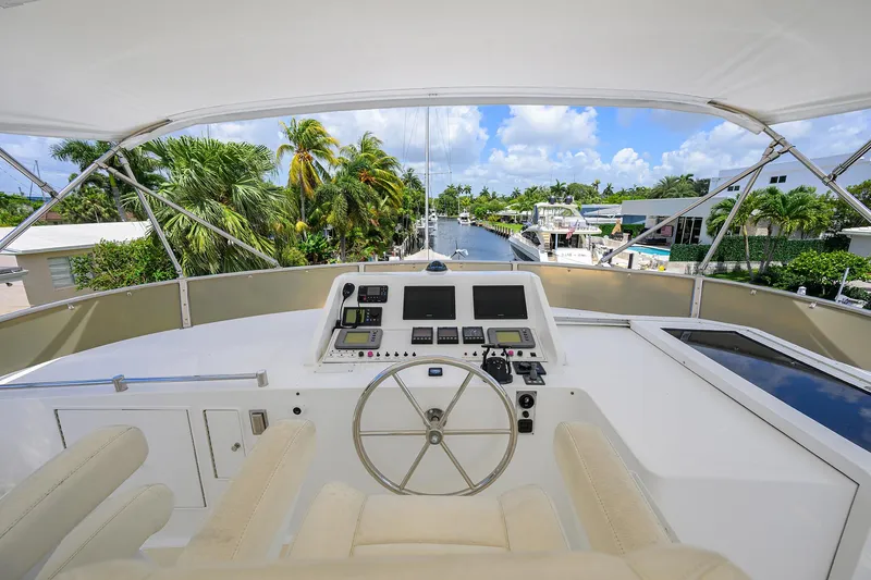 Slide: The Image of Flybridge view of 2001 Ocean Alexander 602 yacht, featuring helm station and tropical canal backdrop. - 31