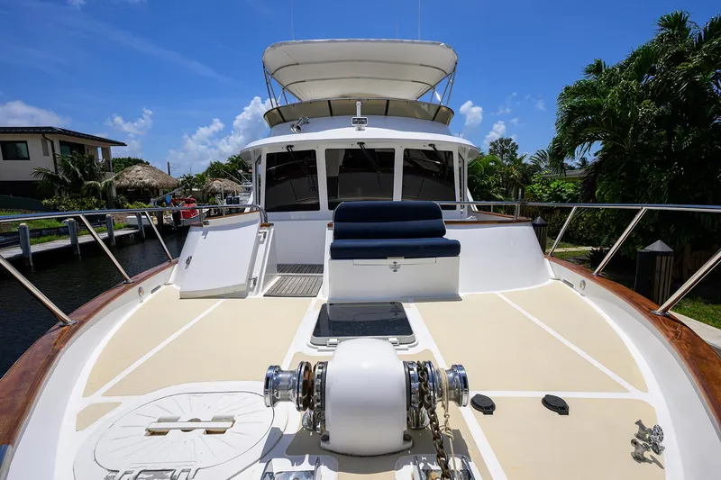 Slide: The Image of 2001 Ocean Alexander 602 yacht deck with seating, docked near lush greenery and blue sky. - 38