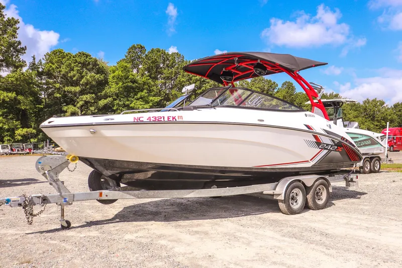 The Image of 2019 Yamaha Boats 242X E-Series on trailer, parked outdoors under blue sky. - 0