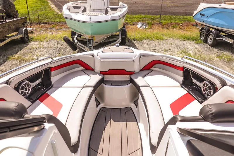 Slide: The Image of 2019 Yamaha Boats 242X E-Series interior with red and white seating, parked outdoors. - 10