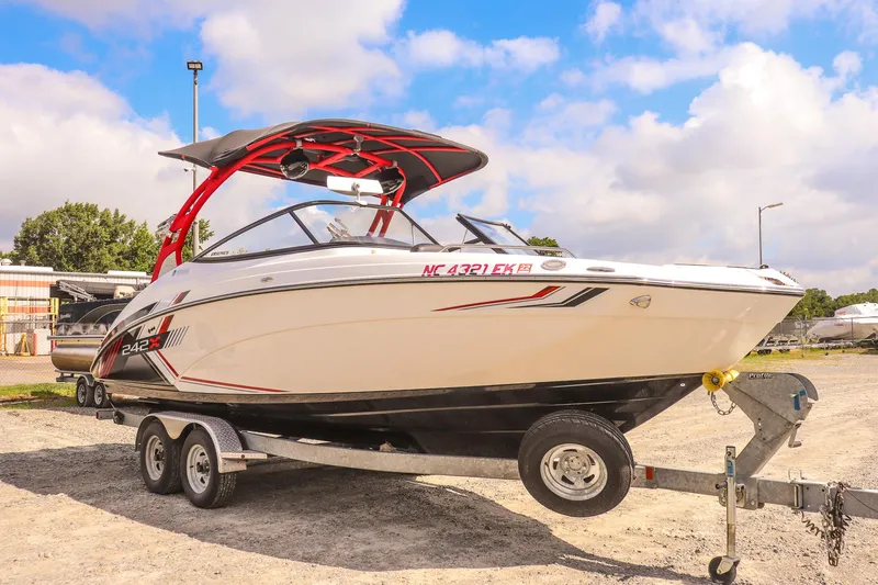 Slide: The Image of 2019 Yamaha Boats 242X E-Series on trailer, parked outdoors under a blue sky. - 2