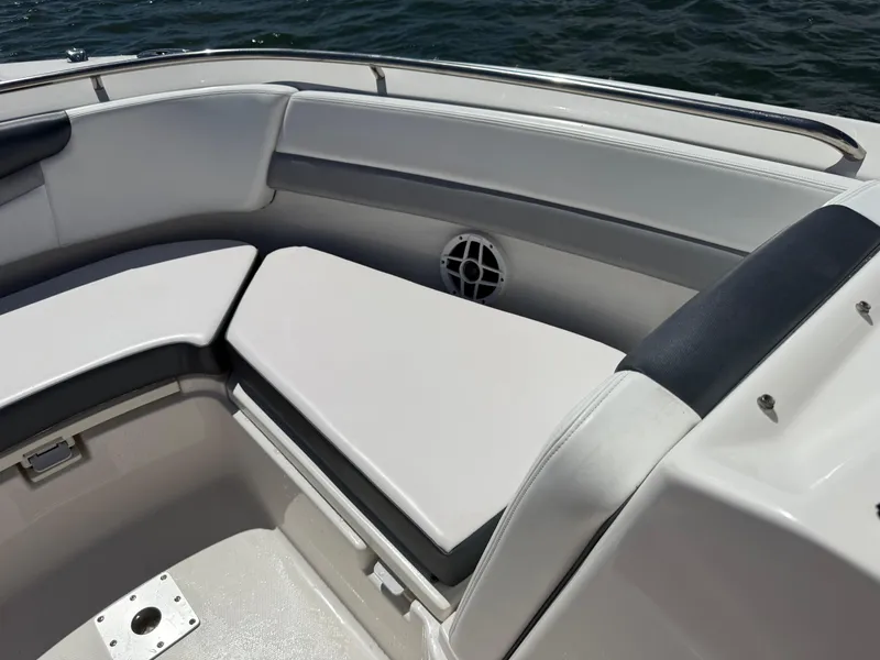 Slide: The Image of 2021 Robalo R247 boat interior with cushioned seating and speaker, on water. - 14