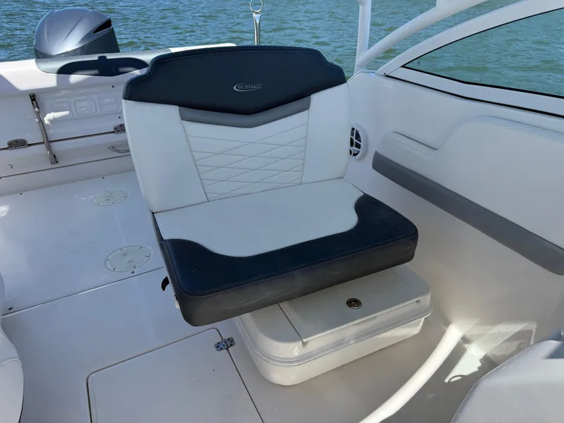 Slide: The Image of 2021 Robalo R247 boat interior with cushioned seating and storage, on calm water. - 20