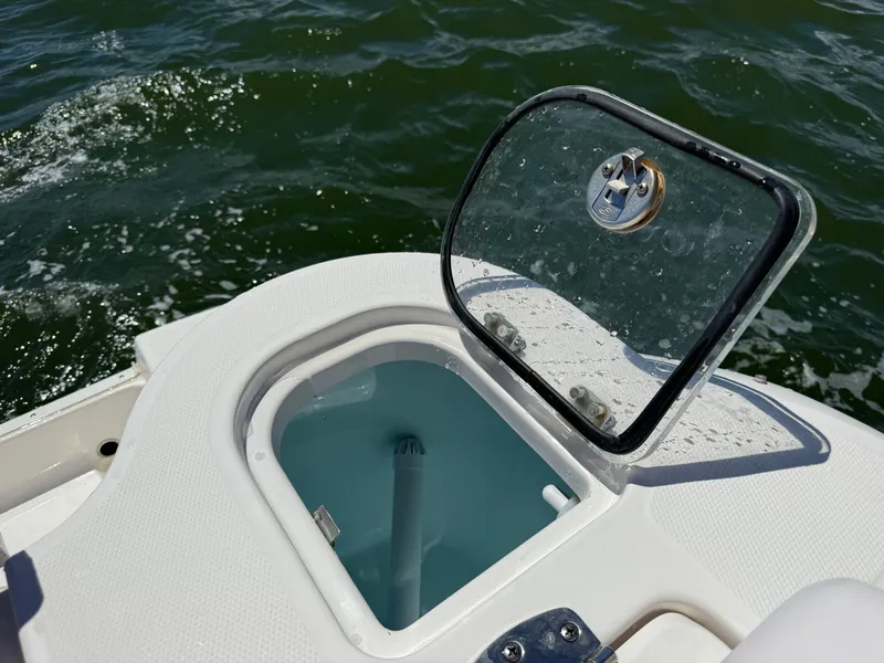 Slide: The Image of Open hatch on 2021 Robalo R247 boat, revealing storage compartment near water. - 26