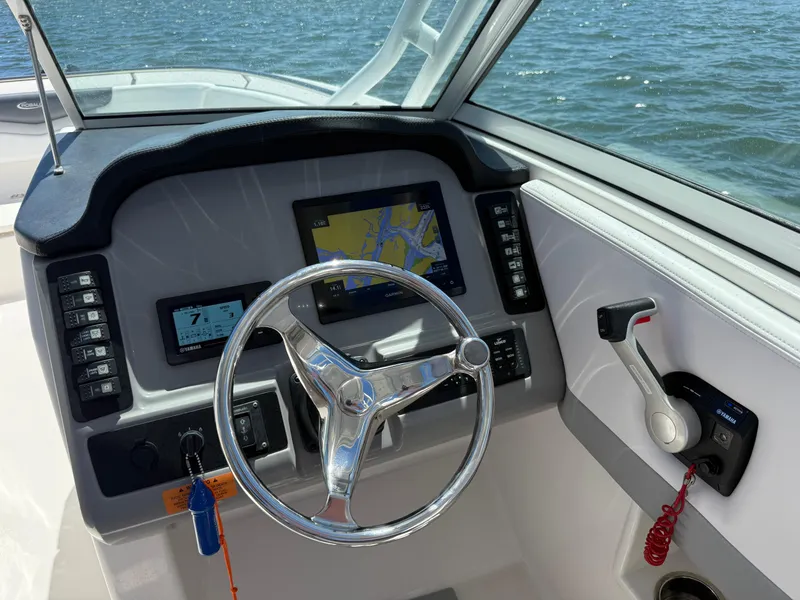Slide: The Image of 2021 Robalo R247 boat dashboard with steering wheel, navigation screens, and throttle controls. - 7