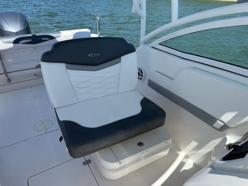Slide: The Image of 2021 Robalo R247 boat interior with cushioned seating and water backdrop. - 9