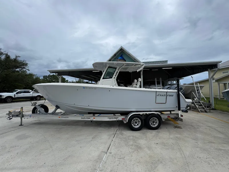 Slide: The Image of 2022 Sailfish 272 CC boat on trailer, parked outdoors under cloudy sky. - 1