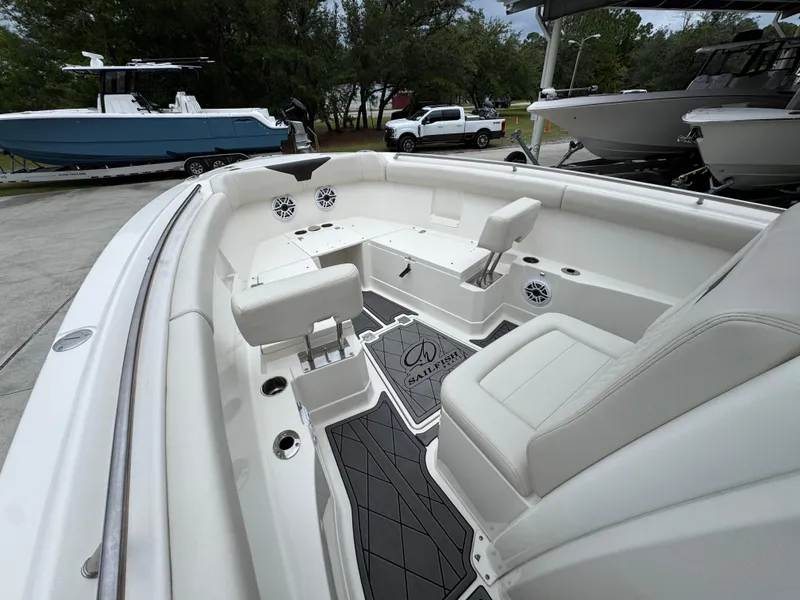Slide: The Image of 2022 Sailfish 272 CC boat interior with seating and speakers, parked outdoors. - 19