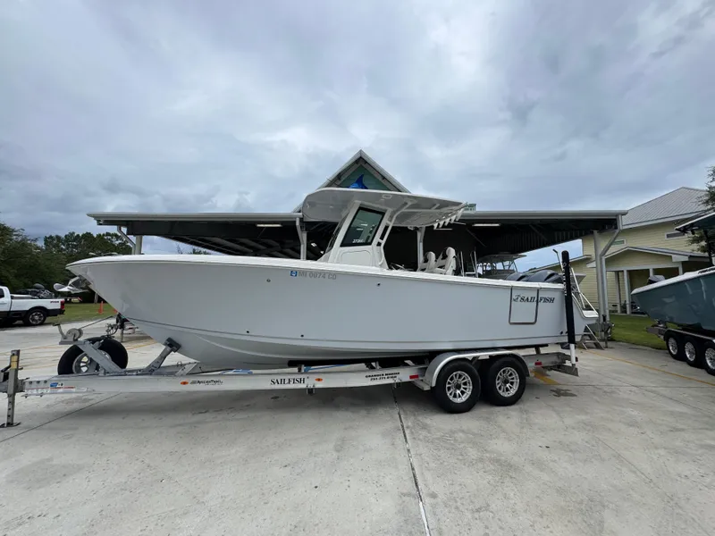 Slide: The Image of 2022 Sailfish 272 CC boat on trailer, parked outdoors under cloudy sky. - 2