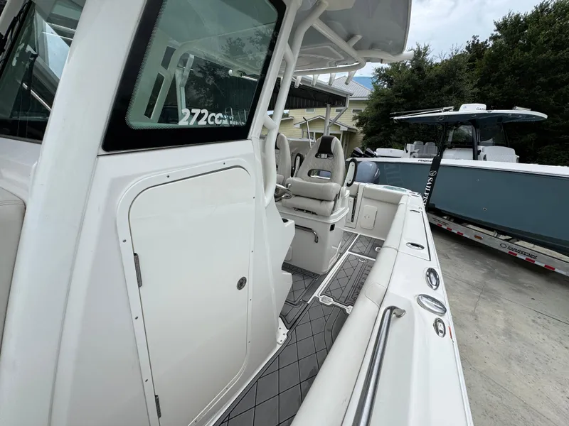 Slide: The Image of 2022 Sailfish 272 CC boat interior with seating and console, docked beside another boat. - 23