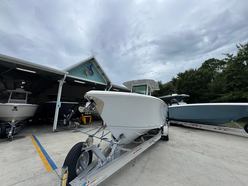 Slide: The Image of 2022 Sailfish 272 CC boat on trailer, parked outside a showroom under cloudy skies. - 5