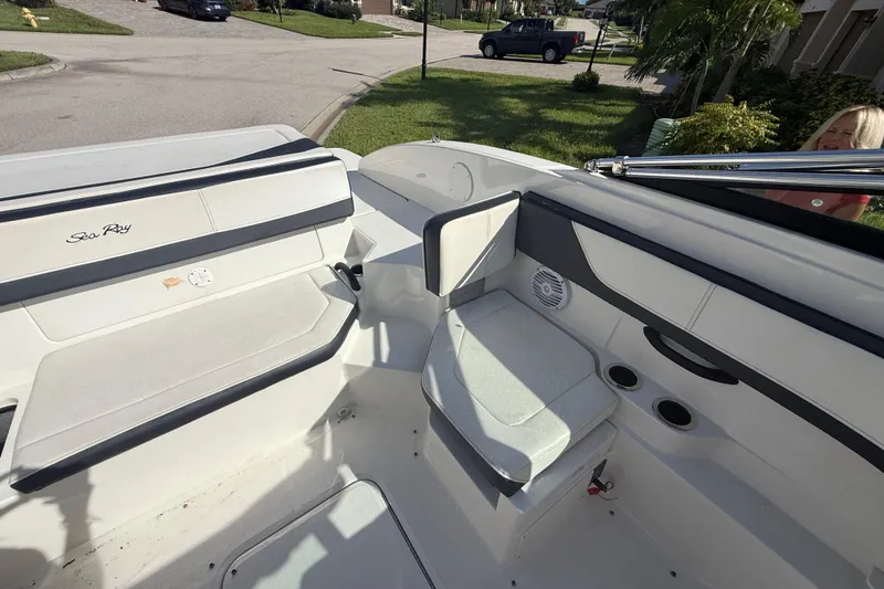 Slide: The Image of 2018 Sea Ray SPX 190 boat interior with seating and cup holders, parked in a residential area. - 16